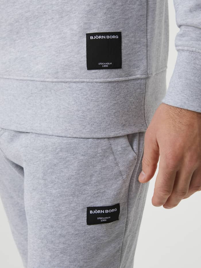 Close-up of the iconic black woven logo label on the men's Centre Crew in Light Grey Melange (Grey), showcasing quality. - Image 5