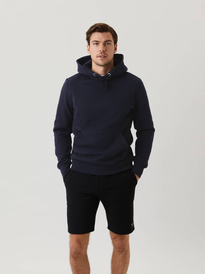 Vue de face d'un homme portant le Centre Hoodie en Night sky (Marine), doté d'une poche kangourou fonctionnelle.