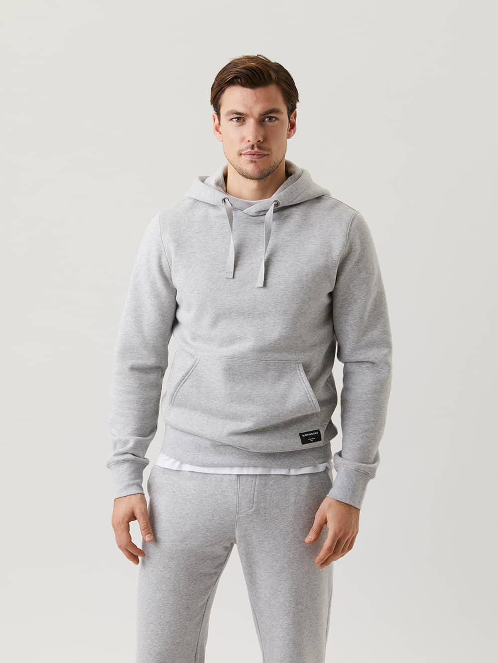 Front view of a man wearing the functional Björn Borg Centre Hoodie in Light Grey Melange (Grey) with a black logo label. - Image 1