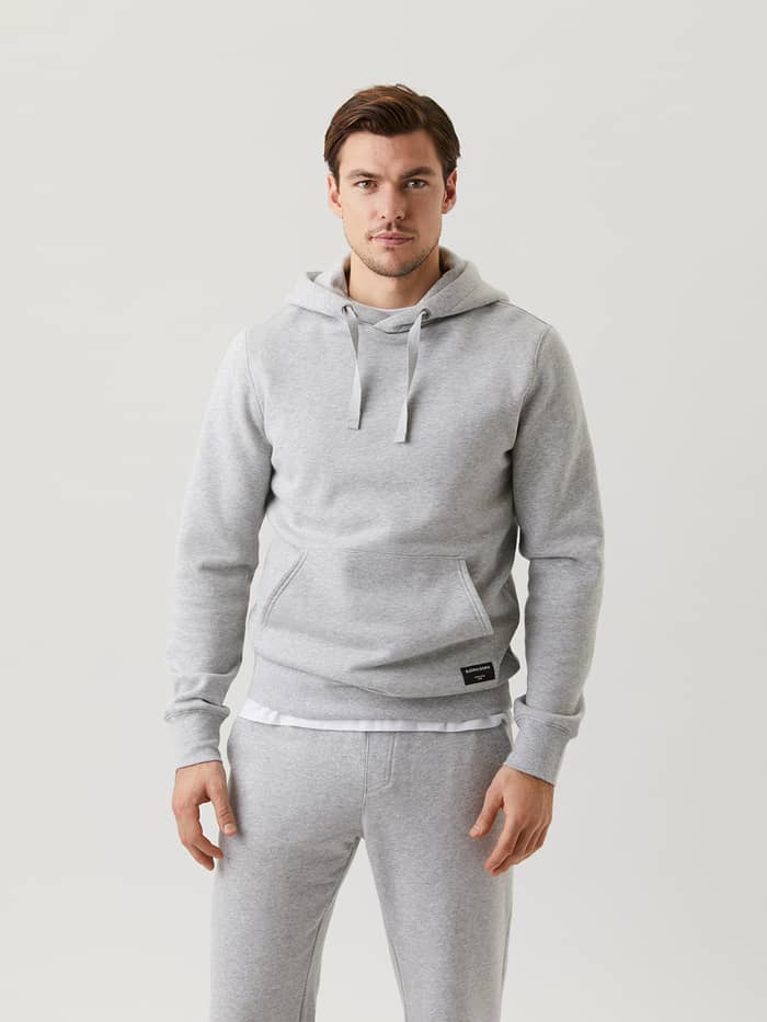 Front view of a man wearing the functional Björn Borg Centre Hoodie in Light Grey Melange (Grey) with a black logo label.