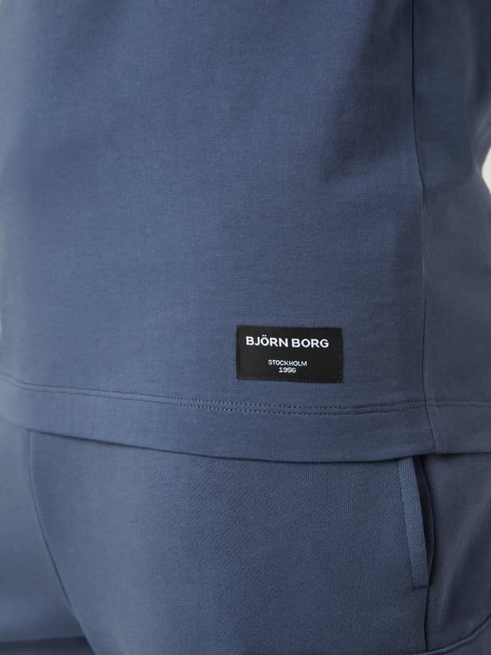 Detail van het heren Centre T-Shirt in Nightshadow Blue (Blauw) met een zwart geweven logolabel aan de zoom. - Image 4