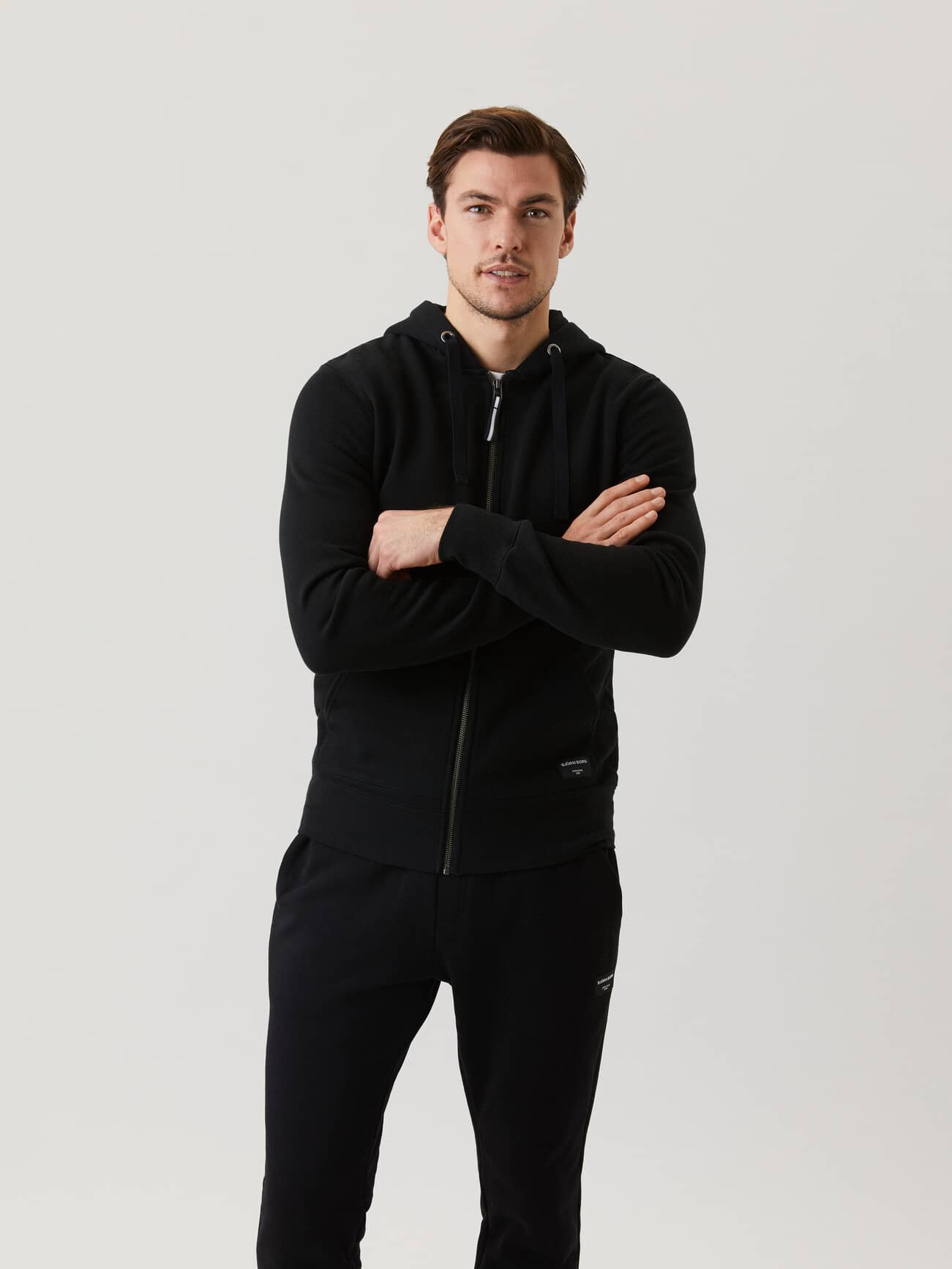 Front view of a man wearing the functional Björn Borg Centre Zip Hood in Black Beauty (Black). - Image 1