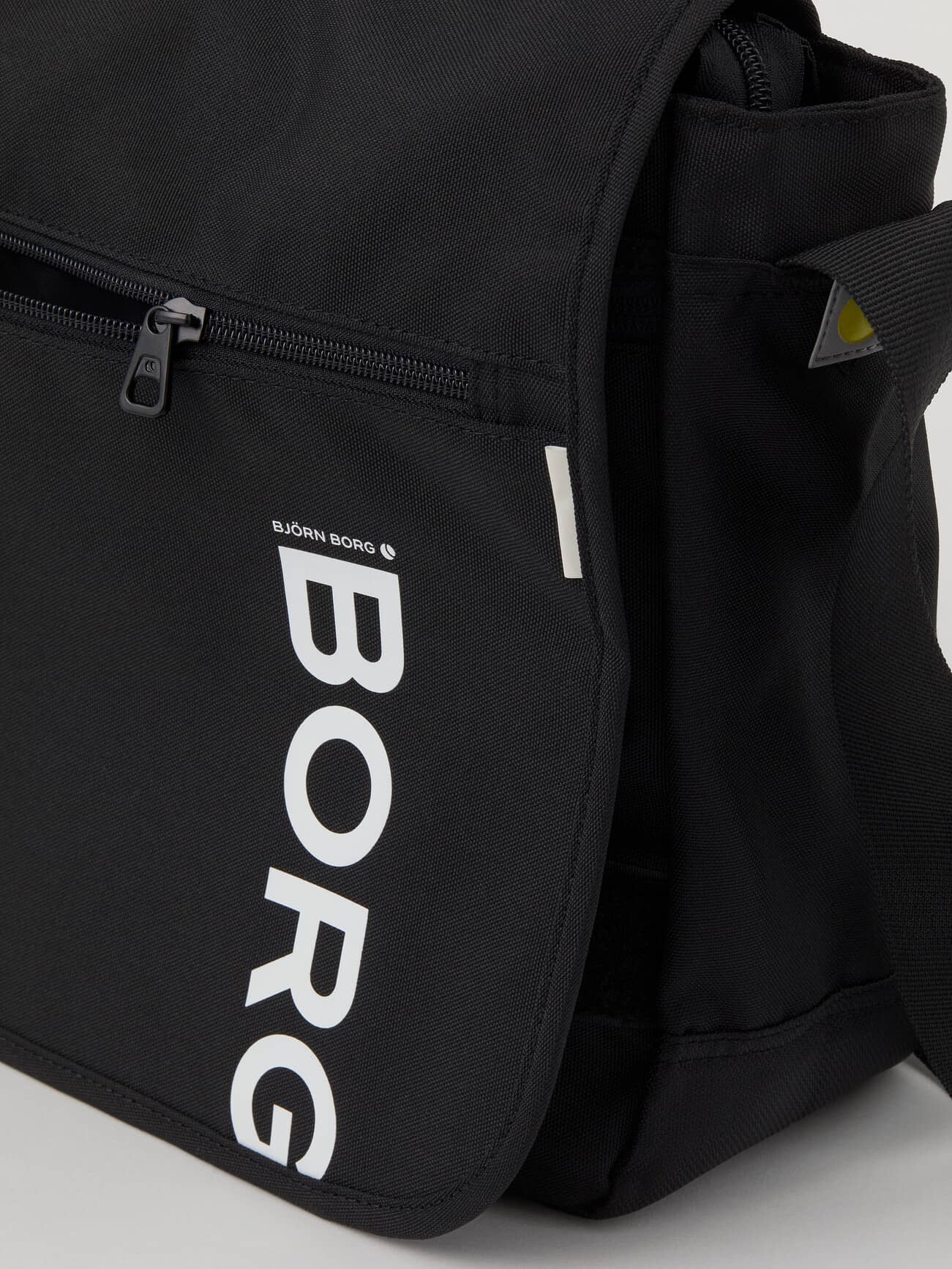 Gedetailleerde close-up van de Björn Borg Core Flapbag 12L in Black Beauty (Zwart) met wit logo en ritsvak. - Image 4