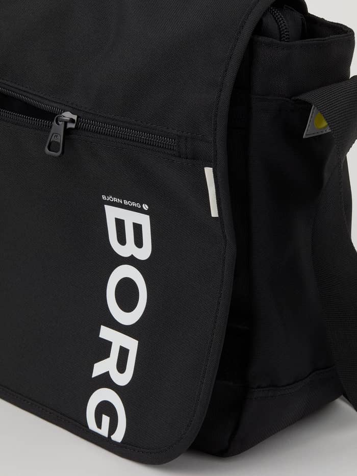 Detailed close-up of the black Björn Borg Core Flapbag 12L showing the white logo and zippered front compartment. - Image 4