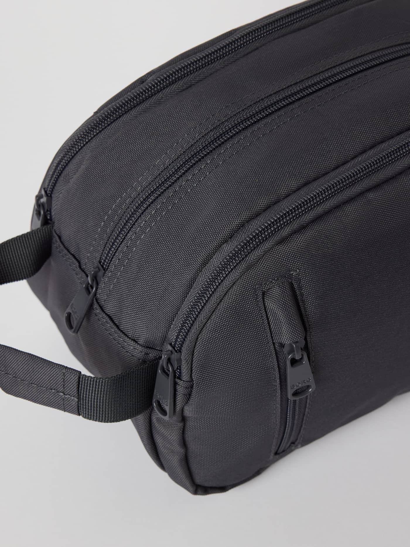 Gros plan de la trousse de toilette Core Wash Bag Standing en Asphalt (Gris) en polyester recyclé avec poignée latérale. - Image 3