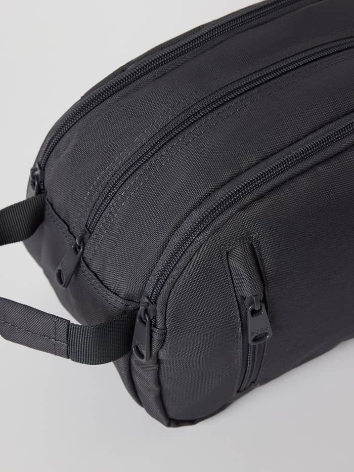 Core Wash Bag Standing in Asphalt (Grijs) van stevig gerecycled polyester met een zijhandvat, getoond in close-up. - Image 3