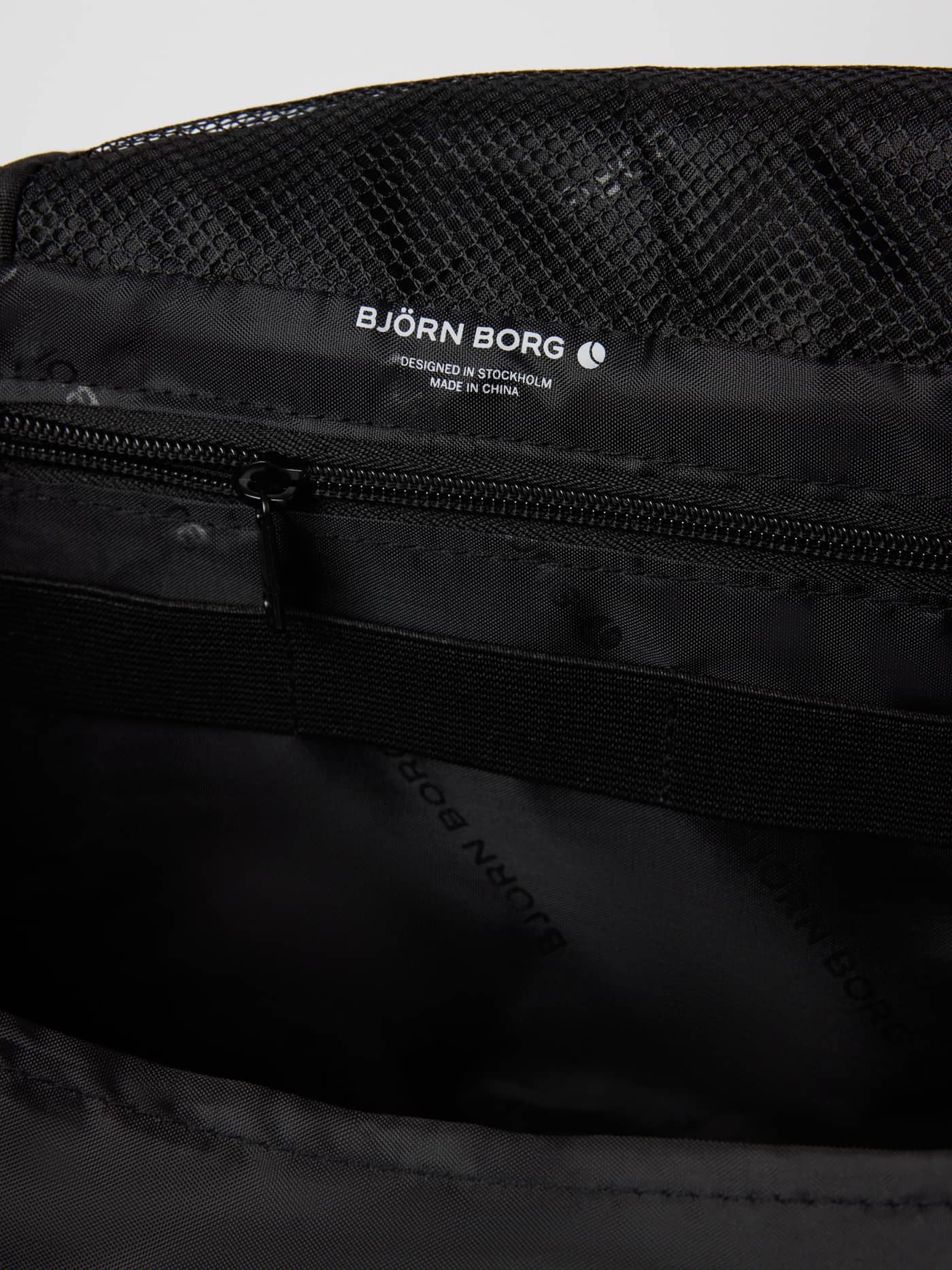 Detailed interior view of the Core Wash Bag Hanging in Asphalt (Grey), featuring a mesh pocket and white logo. - Image 4