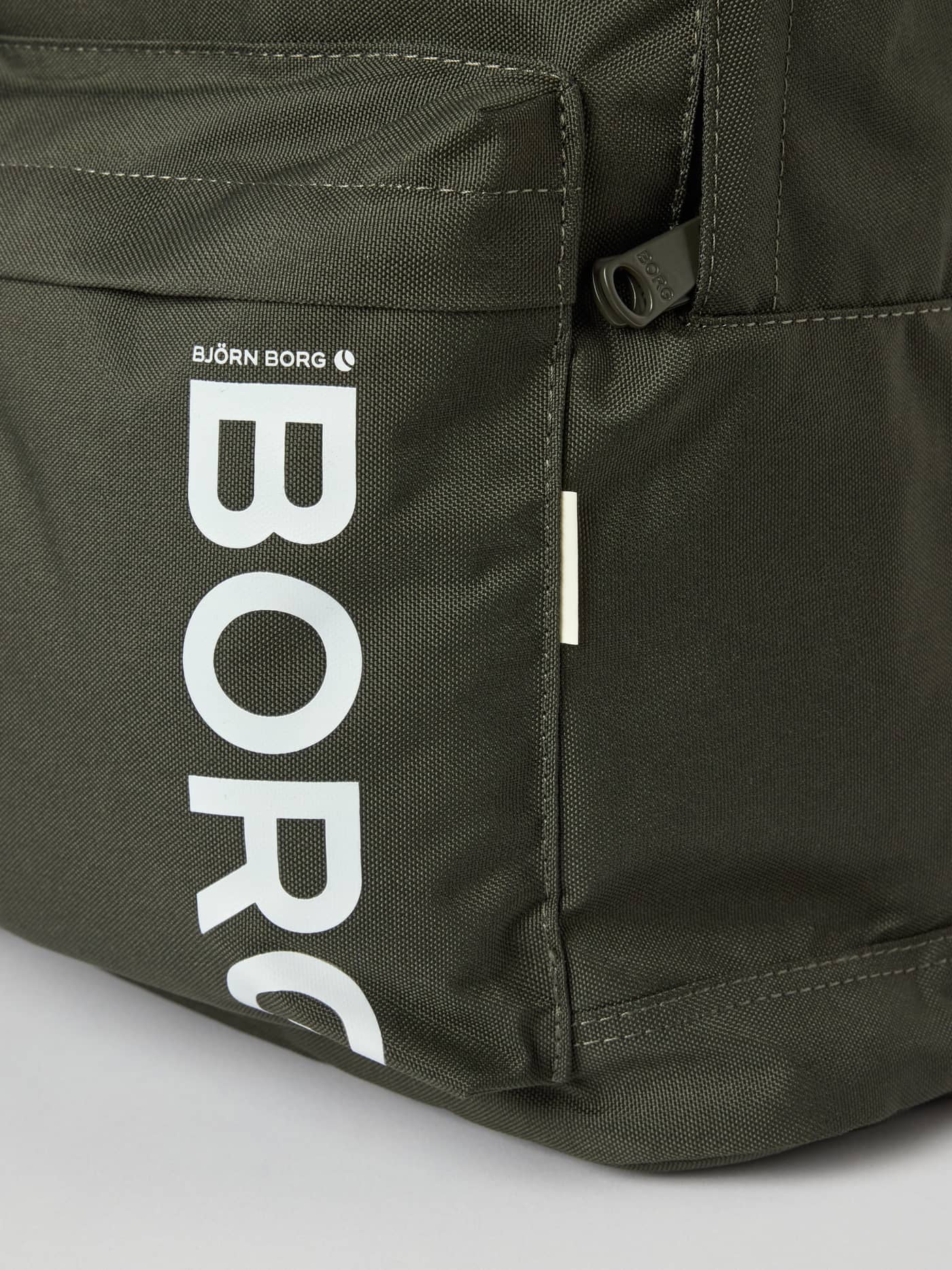 Närbild på den vita BORG-logotypen på Core Street Backpack 21L i Forest Night (Grön) i återvunnen polyester. - Image 4
