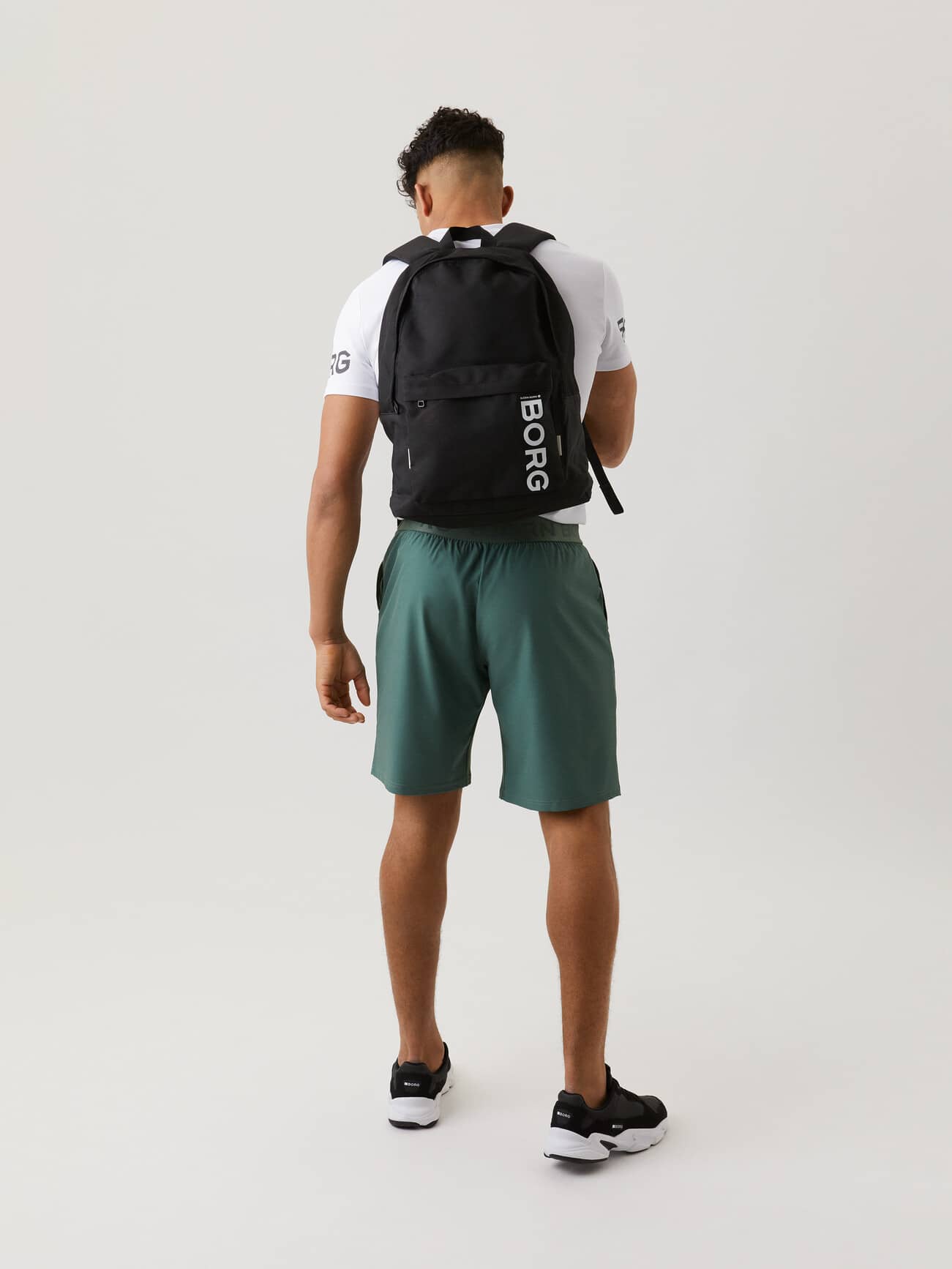 Back view of a man wearing the functional Björn Borg Core Street Backpack 21L in Black Beauty (Black) with a white logo. - Image 2